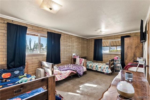 bedroom featuring carpet floors, multiple windows, and brick wall