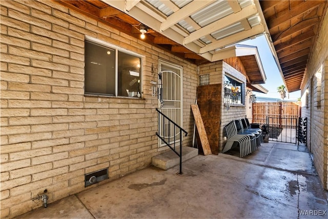 view of side of property with entry steps, a patio area, fence, and brick siding