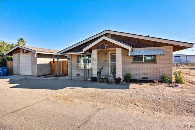 view of front of property featuring crawl space, brick siding, driveway, and fence