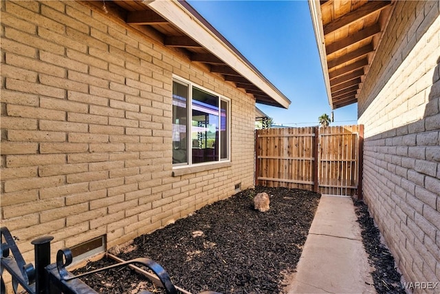 view of side of property featuring brick siding, crawl space, and fence