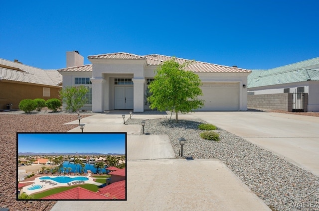 view of front facade featuring an attached garage, a tile roof, concrete driveway, stucco siding, and a chimney