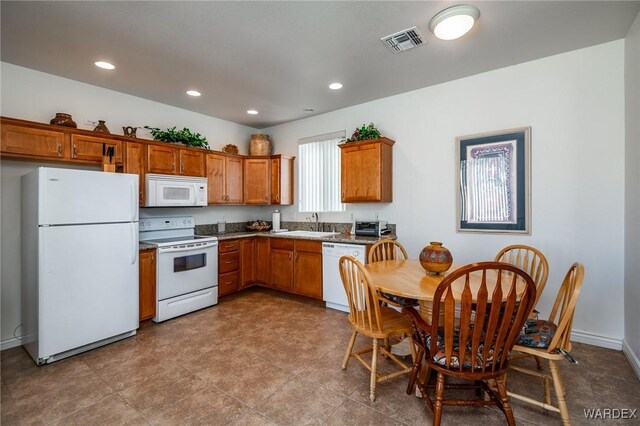 kitchen with white appliances, visible vents, brown cabinets, a sink, and recessed lighting