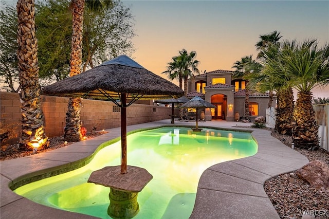 pool at dusk featuring a fenced in pool, a fenced backyard, and a gazebo