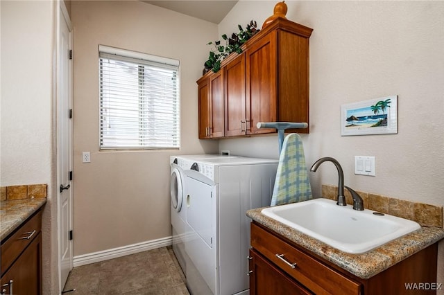 washroom with tile patterned flooring, a sink, baseboards, cabinet space, and washer and clothes dryer