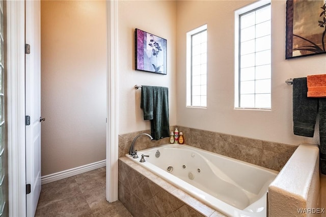 bathroom with baseboards, a tub with jets, and tile patterned flooring