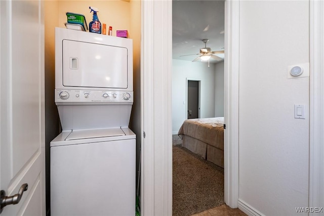 laundry room with ceiling fan, light colored carpet, laundry area, stacked washer / dryer, and baseboards