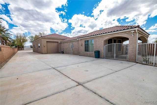 view of front of home with stucco siding, concrete driveway, an attached garage, fence, and a tiled roof