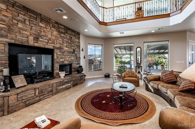 living area with a stone fireplace, a towering ceiling, visible vents, and recessed lighting