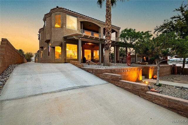 view of front of house with fence, a balcony, and stucco siding