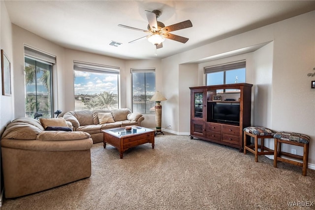 living area featuring carpet, visible vents, baseboards, and ceiling fan