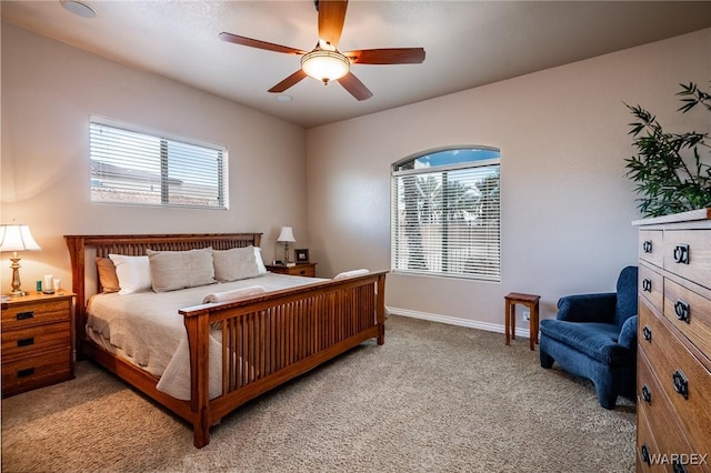 bedroom featuring light carpet, ceiling fan, multiple windows, and baseboards