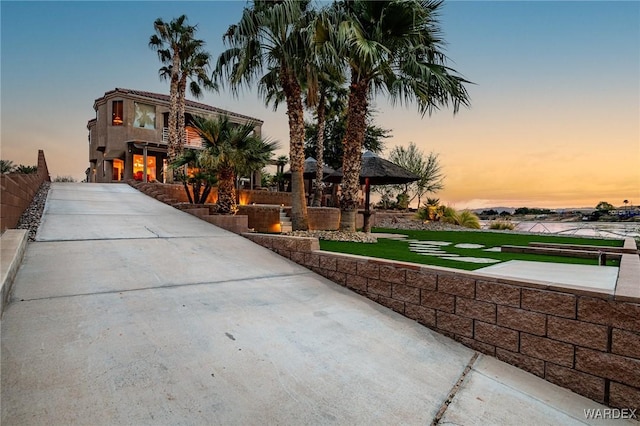 view of community with concrete driveway and fence