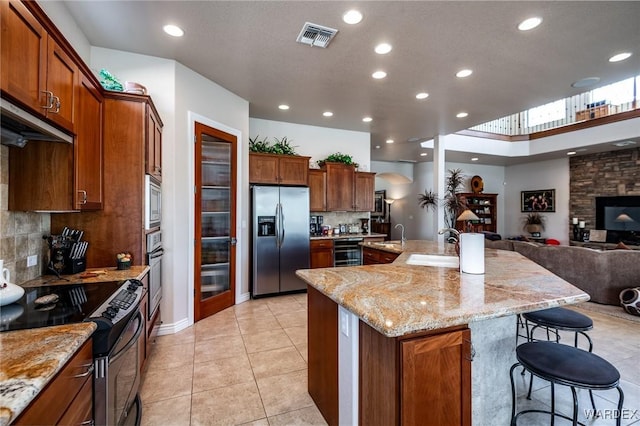 kitchen with visible vents, a spacious island, appliances with stainless steel finishes, a breakfast bar, and open floor plan