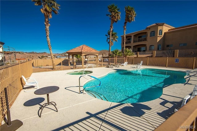 pool featuring a community hot tub, a patio area, fence, and a gazebo