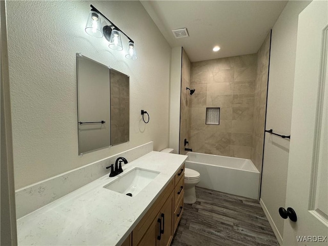 full bathroom with toilet, wood finished floors, visible vents, vanity, and shower / bathing tub combination