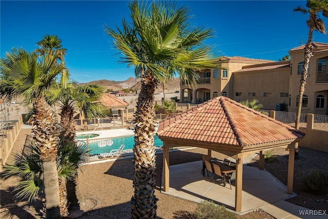 community pool with a gazebo, a patio, fence, and a mountain view