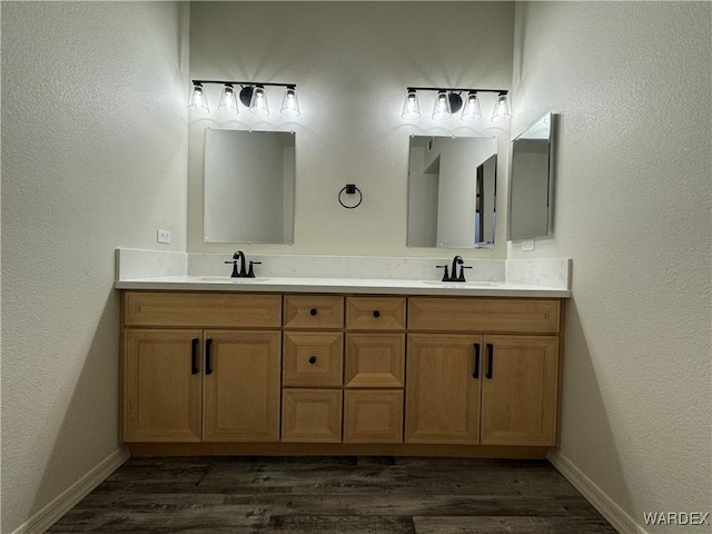 full bathroom with wood finished floors, a sink, and double vanity