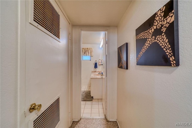 corridor with baseboards, visible vents, and light speckled floor