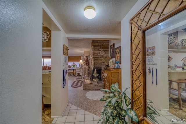 foyer entrance with a stone fireplace, light colored carpet, a textured ceiling, and a textured wall