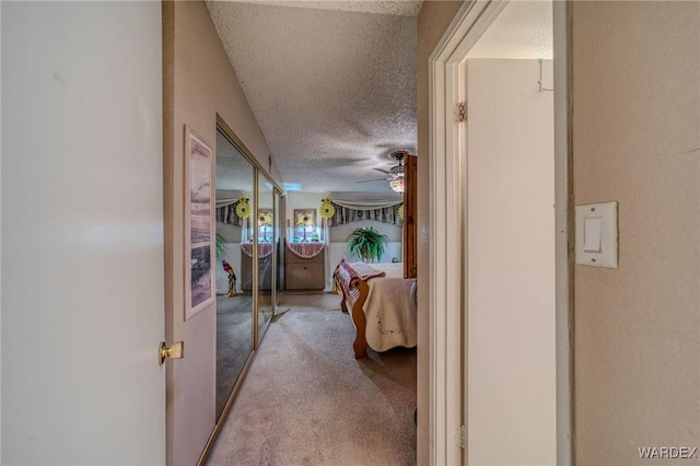 hall with a textured ceiling and carpet flooring