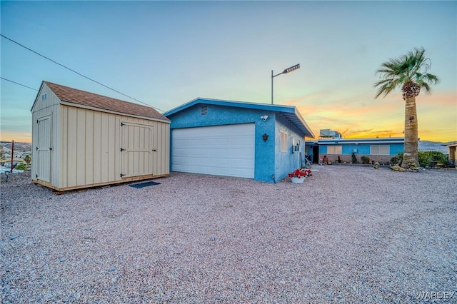 garage at dusk featuring a shed