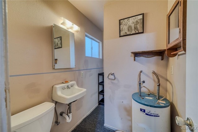 bathroom featuring gas water heater, a sink, and toilet