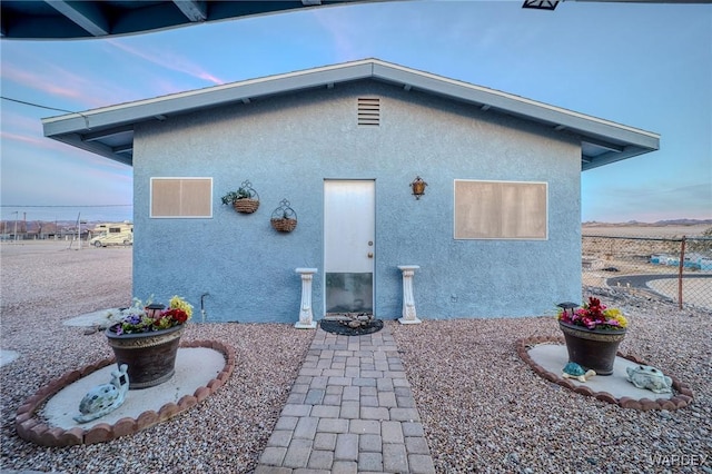 back of property at dusk with fence and stucco siding