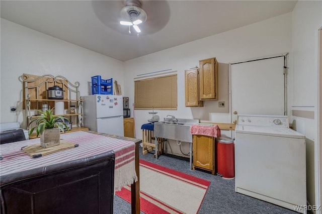 kitchen with ceiling fan, a sink, freestanding refrigerator, dark colored carpet, and washer / dryer