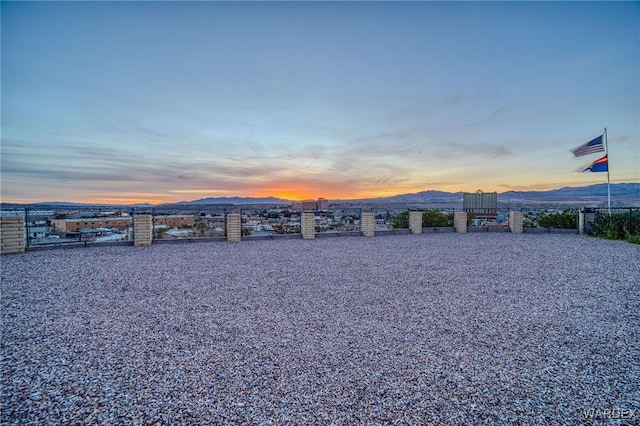 yard at dusk featuring fence and a mountain view