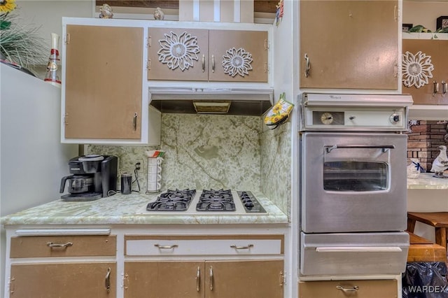 kitchen featuring light countertops, under cabinet range hood, stainless steel oven, backsplash, and gas cooktop