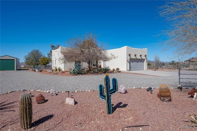 pueblo-style house with stucco siding, driveway, and a garage