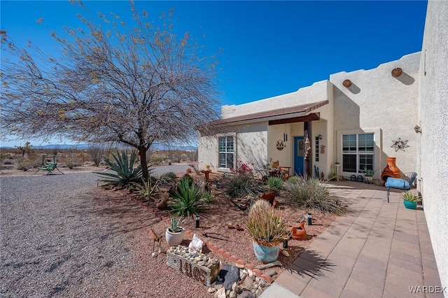 exterior space with stucco siding and a patio