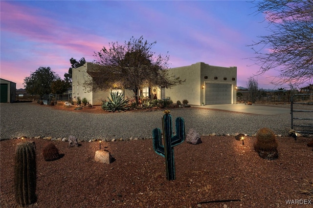 adobe home with an attached garage, driveway, and stucco siding