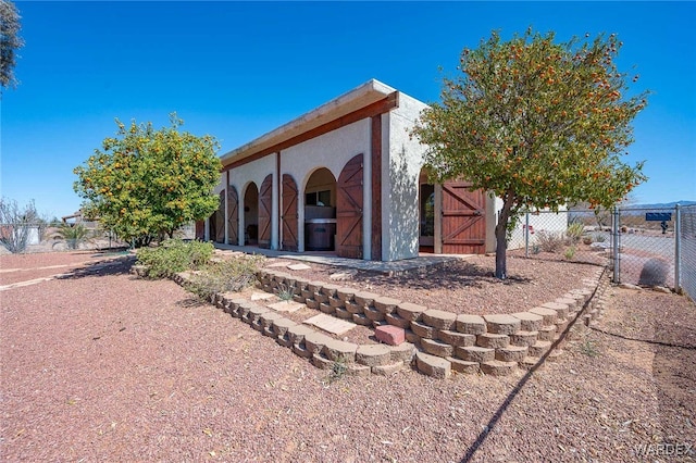 exterior space featuring stucco siding, an outdoor structure, and fence