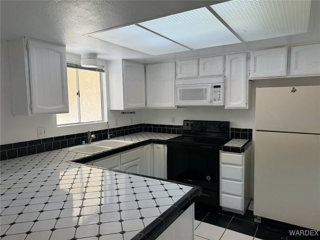 kitchen featuring white appliances, white cabinetry, tile counters, and a sink