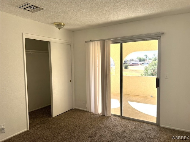 interior space with a closet, dark carpet, visible vents, and access to exterior