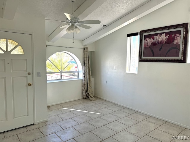 entryway with a ceiling fan, vaulted ceiling, a textured ceiling, and light tile patterned floors