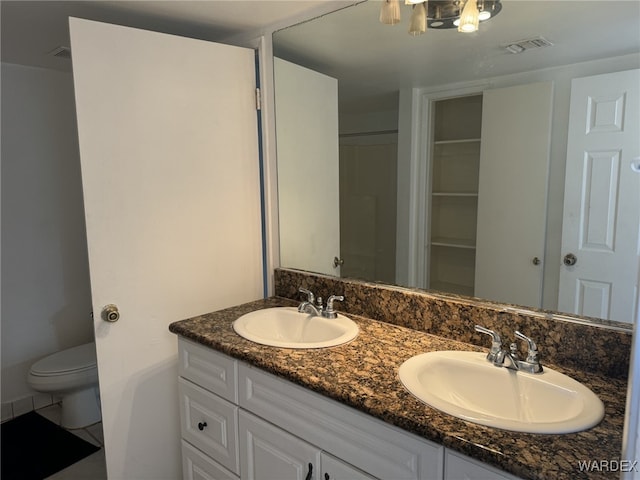 full bathroom with visible vents, a sink, toilet, and double vanity