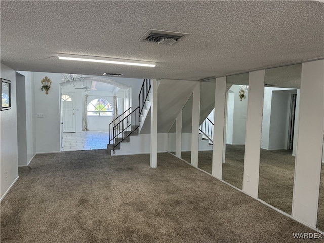 interior space featuring a textured ceiling, arched walkways, visible vents, stairway, and carpet