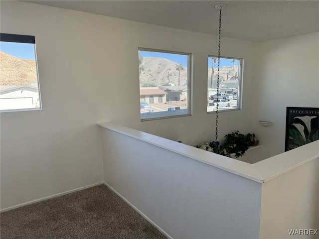 hallway featuring carpet, a mountain view, and baseboards