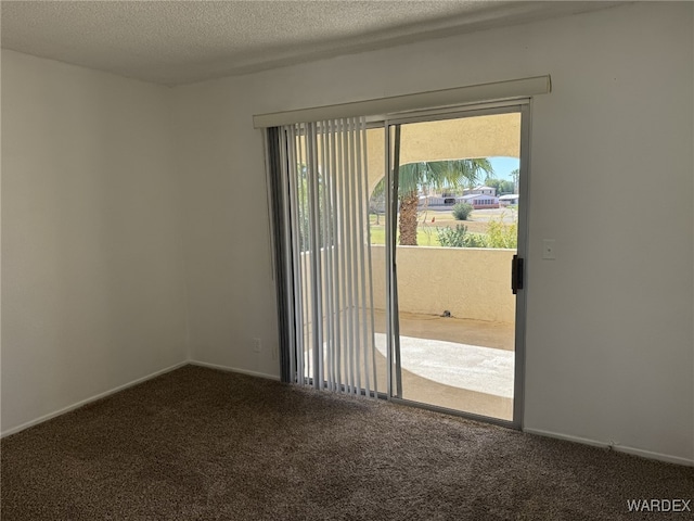 spare room featuring baseboards, dark carpet, and a textured ceiling