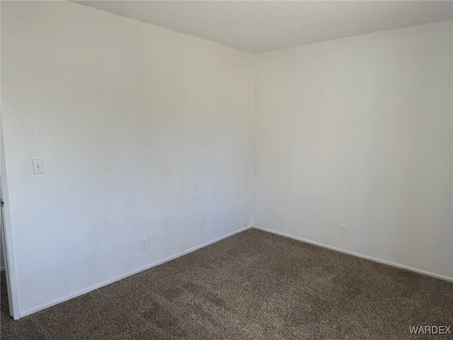 unfurnished room featuring a textured ceiling, dark colored carpet, and baseboards