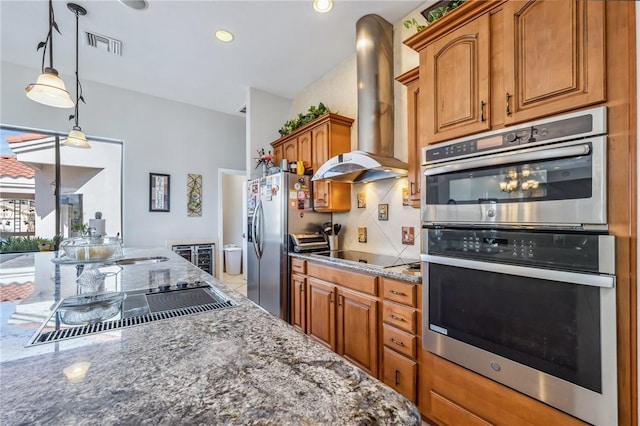 1878 E Fairway Bnd, Fort Mohave, AZ 86426 - kitchen featuring wall chimney exhaust hood, stainless steel appliances, dark stone counters, brown cabinets, and decorative light fixtures
