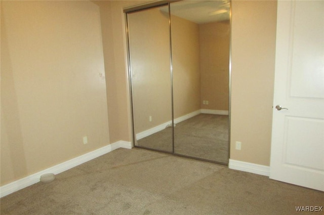 unfurnished bedroom featuring a closet, carpet flooring, and baseboards