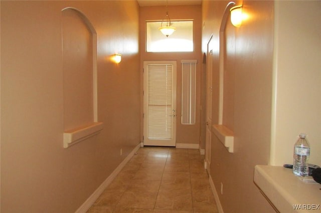 entryway featuring baseboards, arched walkways, and tile patterned flooring