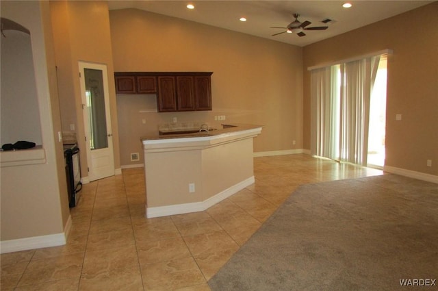 kitchen featuring electric range, open floor plan, a ceiling fan, and light countertops