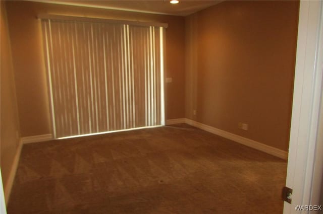 empty room featuring baseboards, dark colored carpet, and recessed lighting