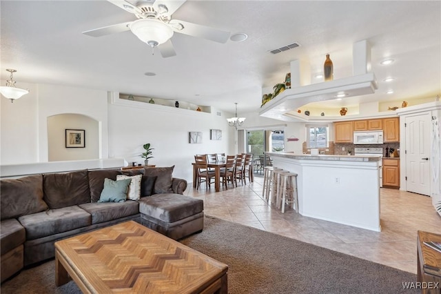 living room with light tile patterned floors, recessed lighting, visible vents, and ceiling fan with notable chandelier