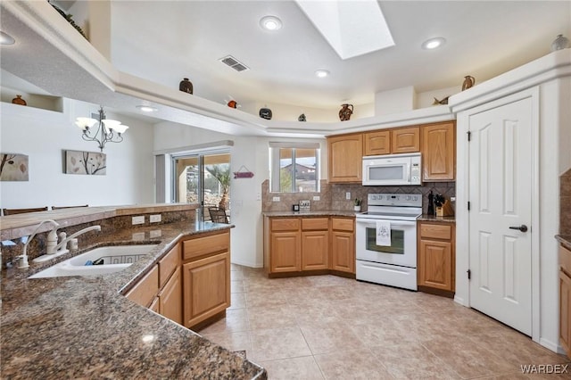 kitchen with white appliances, a skylight, visible vents, a sink, and backsplash