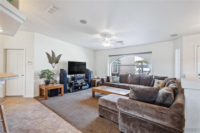 living area with light tile patterned floors, visible vents, a ceiling fan, and light colored carpet